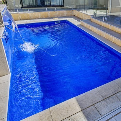 Fibreglass pool with deck water jets and glass fencing